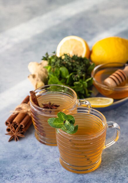 Photo two cups with hot tea with herbs spices lemon ginger root and honey herbal tea