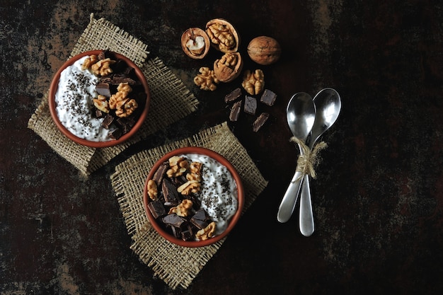 Two cups with yogurt with chia seeds, walnuts and dark chocolate. Breakfast or dessert for two. Healthy food.