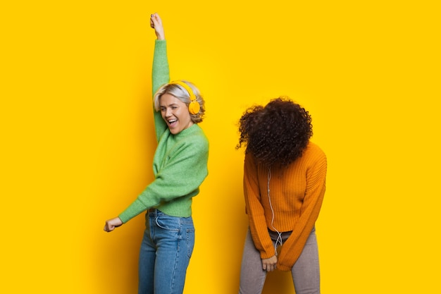 Two curly haired caucasian women are dancing while listening to music