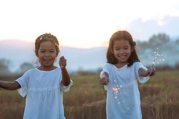두 귀여운 아시아 아이 소녀는 쌀 기분이 축제에 불 폭죽 놀고있다