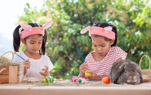 Two cute asian child girls drawing and painting on easter eggs together prepare for easter day