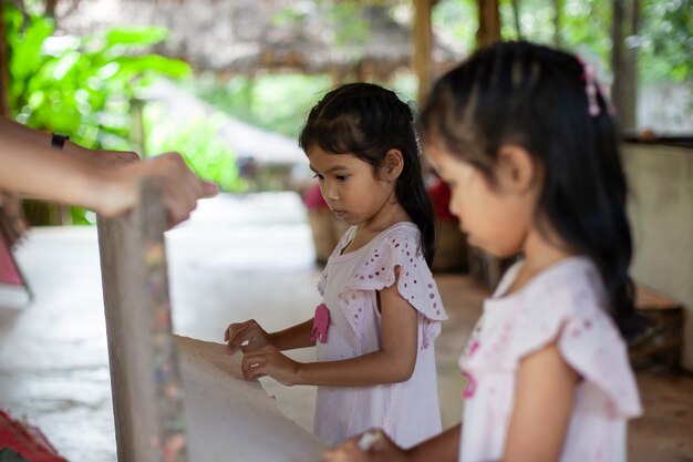 象の糞からリサイクル紙を作る方法を学ぶ2つのかわいいアジアの子供の女の子