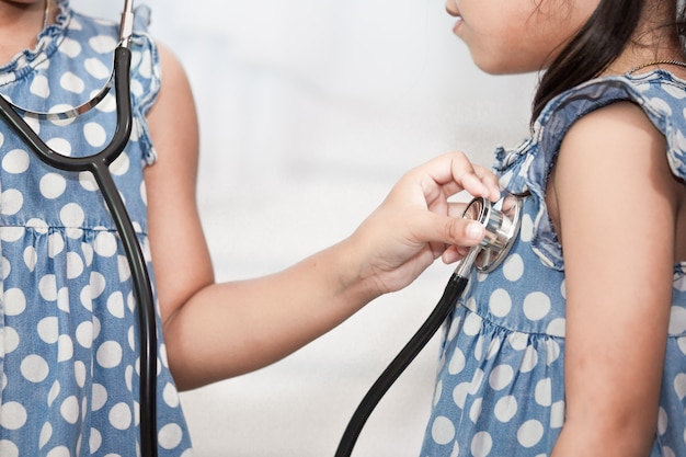 Two cute asian little child girls playing doctor and patient with stethoscope together