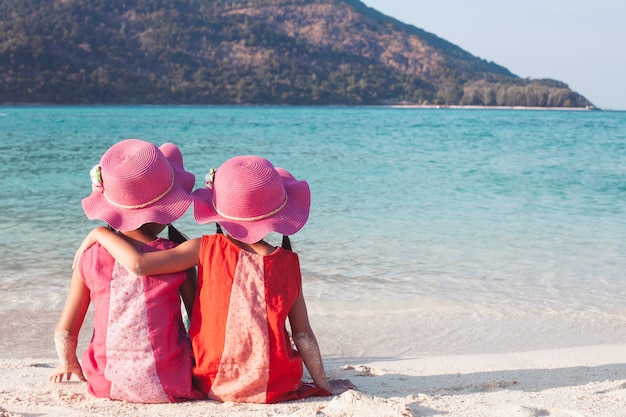 Two cute asian little child girls sitting and hugging each other  on the beach