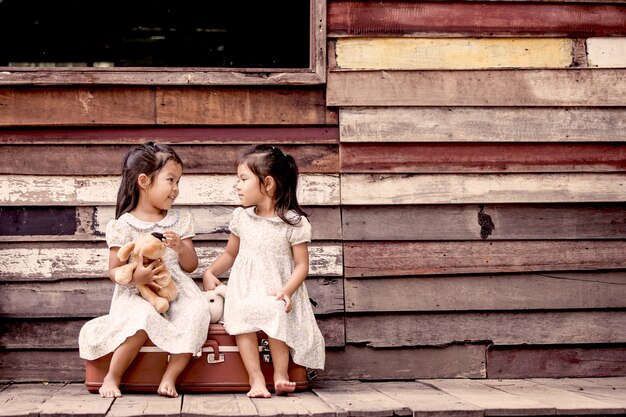 Two cute asian little girls playing with teddy bears.