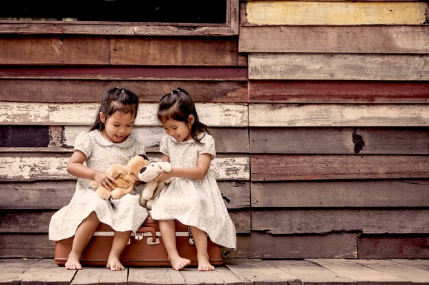 Two cute asian little girls playing with teddy bears.