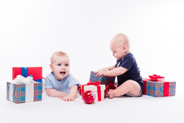 Two cute baby sitting among the Christmas gift box