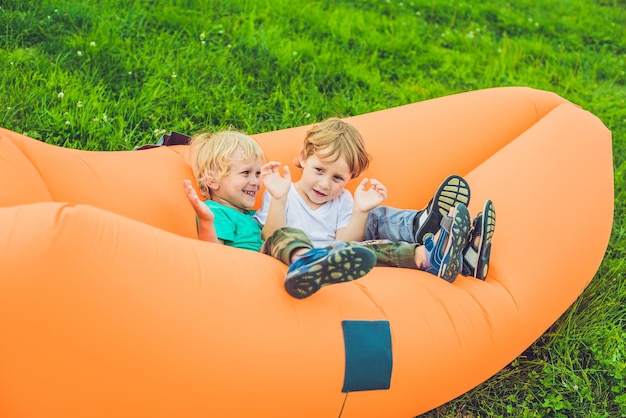 Two cute boys resting on an air sofa in the park.