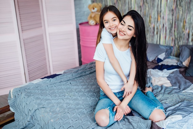 Two cute caucasian sisters hugging on the bed