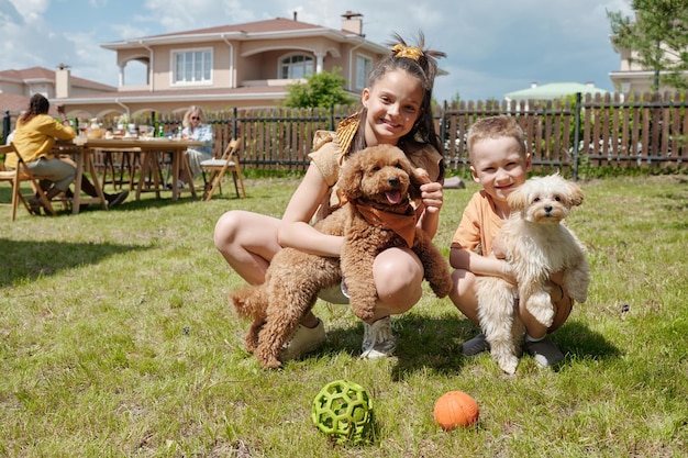 Due bambini allegri svegli che giocano con i loro animali domestici del cane sull'erba verde