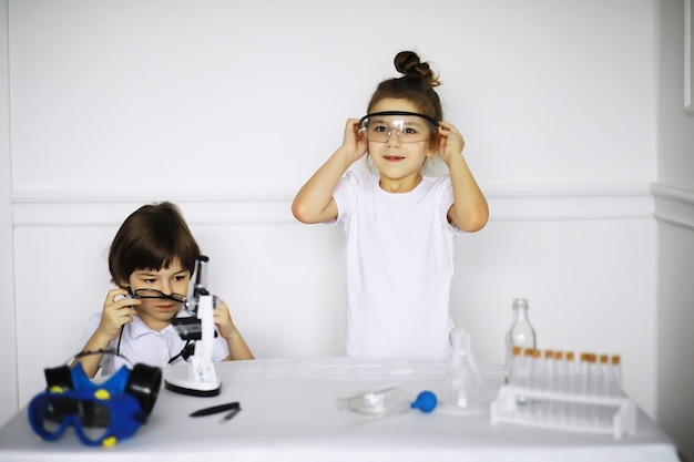 Foto due bambini carini alla lezione di chimica che fanno esperimenti isolati su sfondo bianco