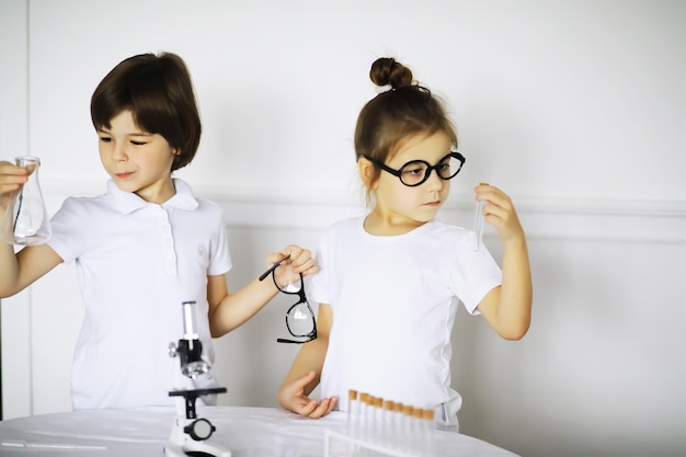 Two cute children at chemistry lesson making experiments isolated on white background