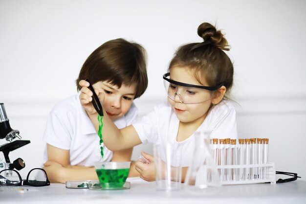 Two cute children at chemistry lesson making experiments isolated on white background