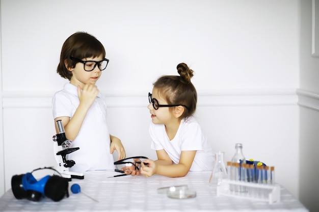 Two cute children at chemistry lesson making experiments isolated on white background