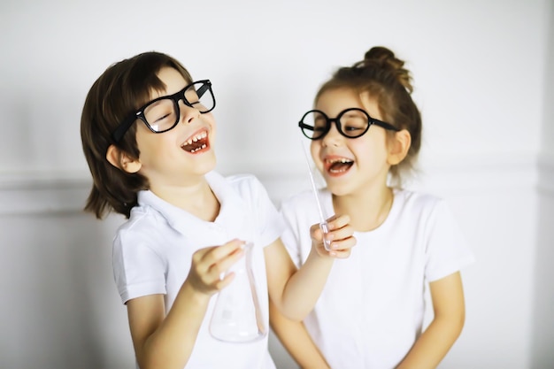 Two cute children at chemistry lesson making experiments isolated on white background