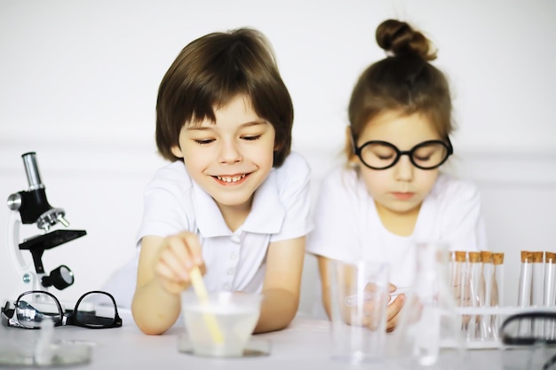 Двое милых детей на уроке химии проводят эксперименты на белом фоне