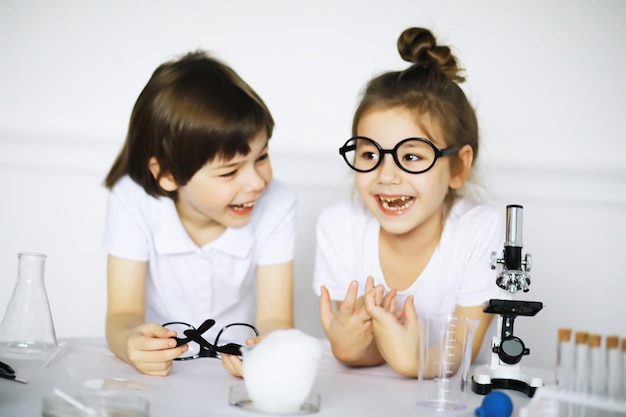 Two cute children at chemistry lesson making experiments on white background