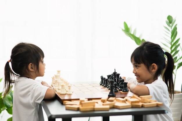 Двое милых детей играют в шахматы дома