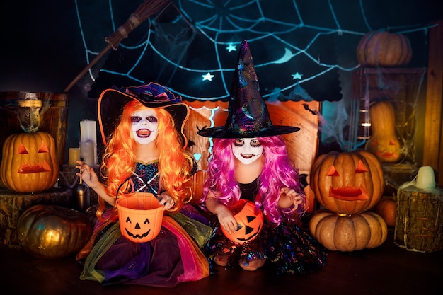 Two cute funny sisters celebrate the holiday. Jolly children in carnival costumes ready for Halloween in halloween decorations