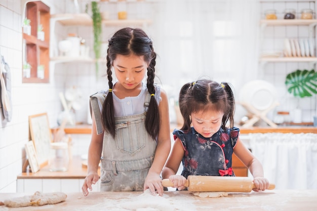 Two cute girls making cake cooking in kitchen at home