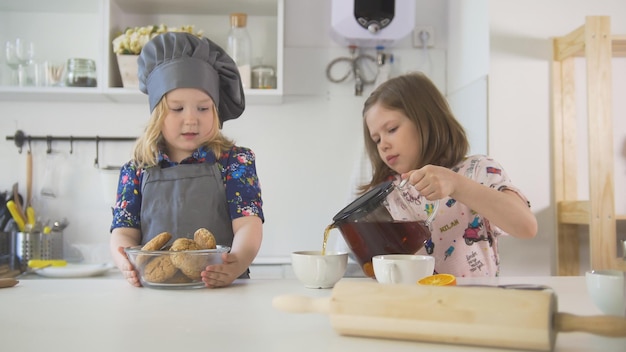 Two cute little girls decorating cookies with jam close up