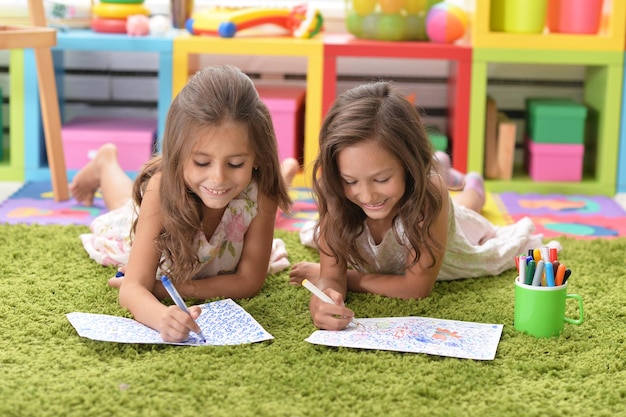 Two cute little girls drawing with pencils