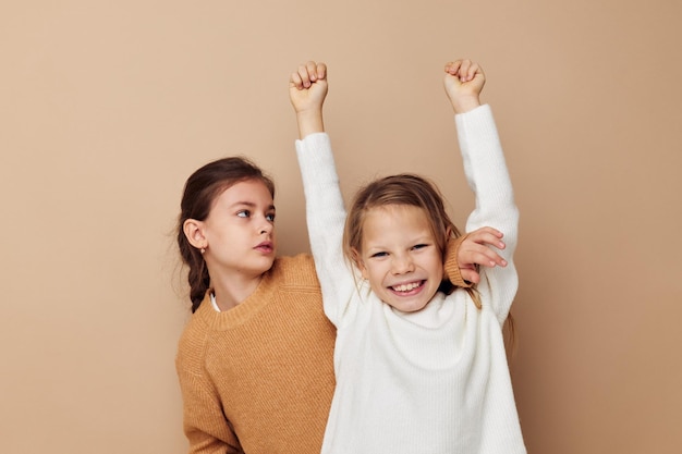 Two cute little girls hug friendship lifestyle beige background