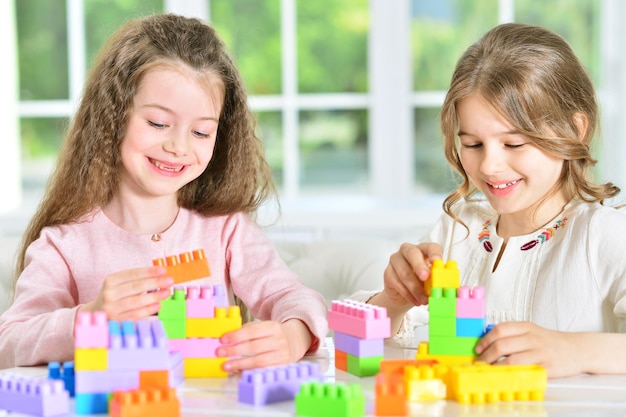 two cute little girls playing with colorful plastic blocks