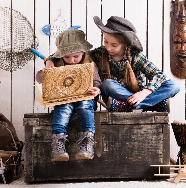 Two cute little girls on wooden chest watching album