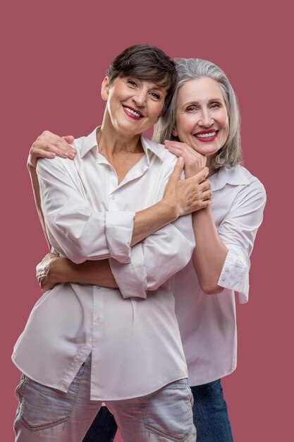 Two cute mature women standing together and hugging