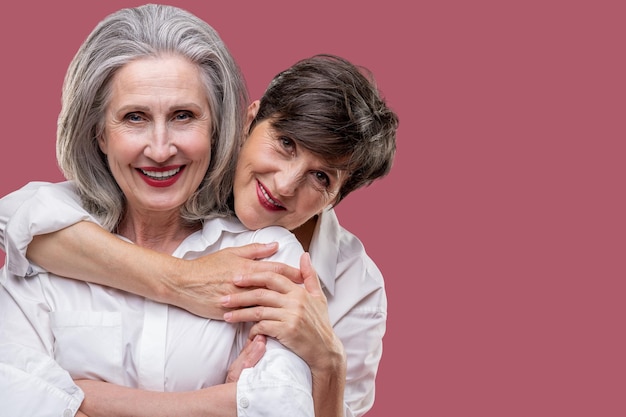 Two cute mature women standing together and hugging