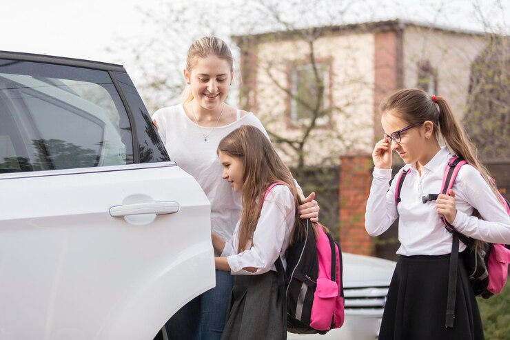 学校に乗るために車に乗る2人のかわいい女子学生
