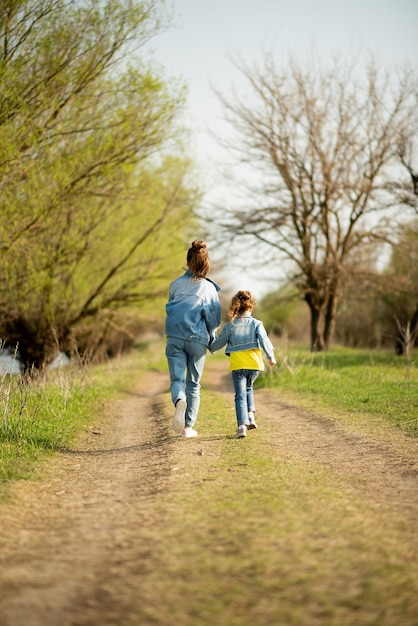 Two cute sister girls are running down an empty country road\
spring freedom childhood family