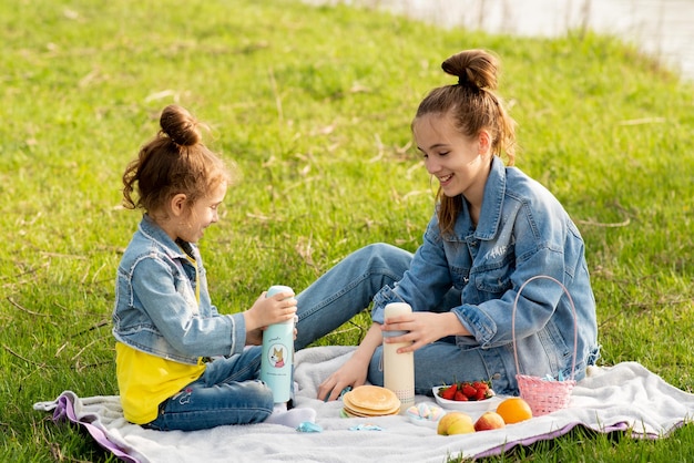 ネイチャーファミリーバケーションスプリング川沿いの街の外でピクニックをしている2人のかわいい姉妹の女の子