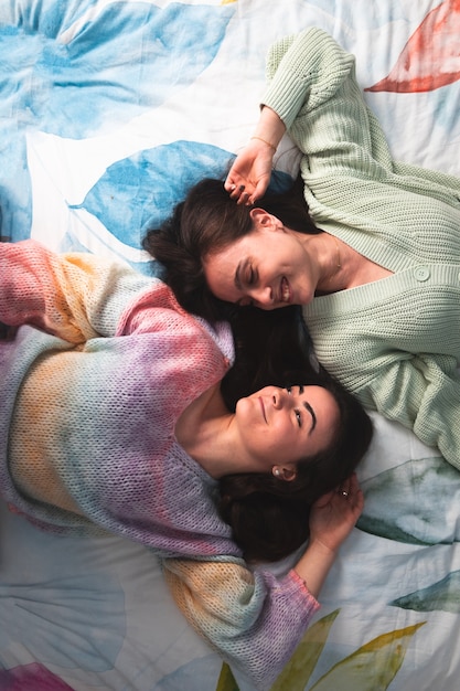 Photo two cute young women laying on a bed