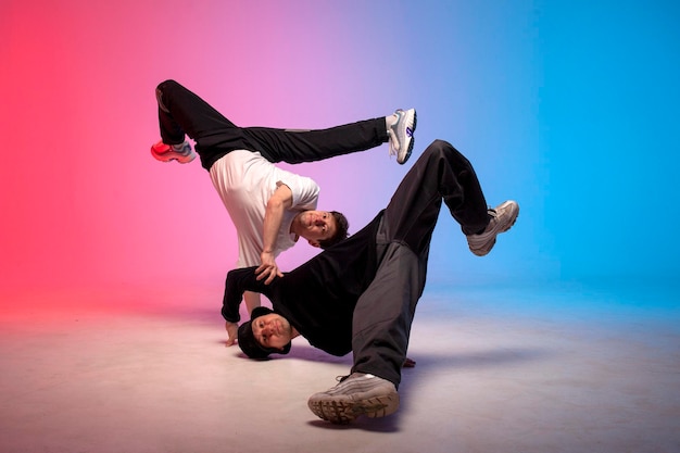 Two dancer guys break dance on red blue background and do trick together male acrobats