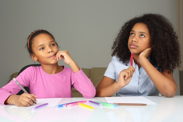 Two dark-skinned girls dream about the idea of drawing
