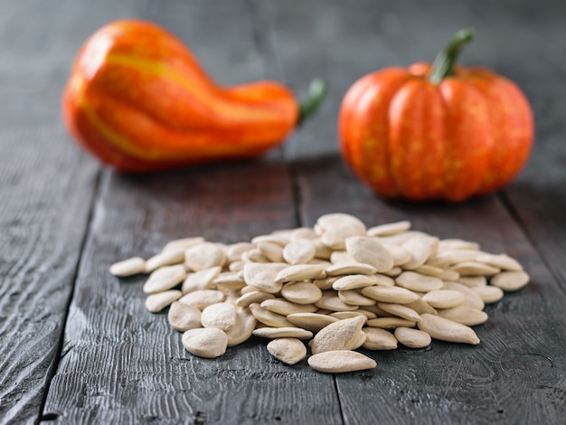 Photo two decorative ripe pumpkins and a bunch of pumpkin seeds on a rustic table