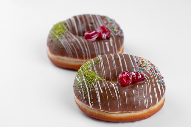 Two delicious chocolate donuts placed on a white table . 