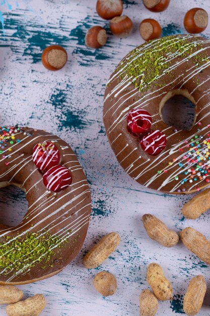 Two delicious chocolate donuts with healthy nuts placed on a stone table . 
