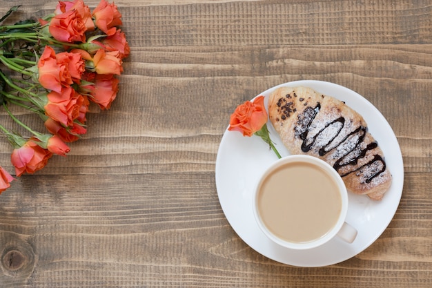 Two delicious freshly baked chocolate croissants and cup of coffee on wooden board. Top view. Breakfast concept. Copy space.