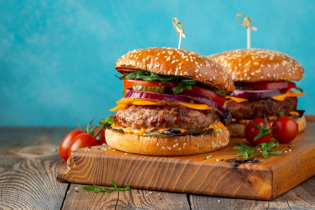 Due deliziosi hamburger fatti in casa di formaggio di manzo e verdure su un vecchio tavolo di legno grasso malsano per...