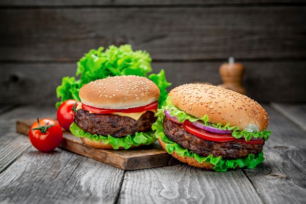 古い木製のテーブルに牛肉の2つのおいしい自家製ハンバーガー脂肪の不健康な食べ物のクローズアップ