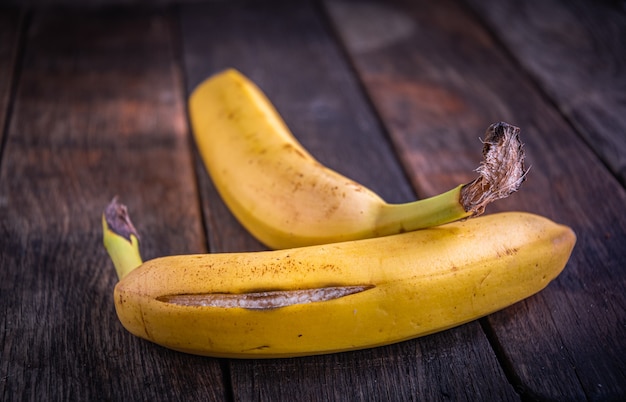 껍질이 벗겨진 맛있는 익은 바나나 두 개는 오래된 나무 판자에 놓여 있습니다