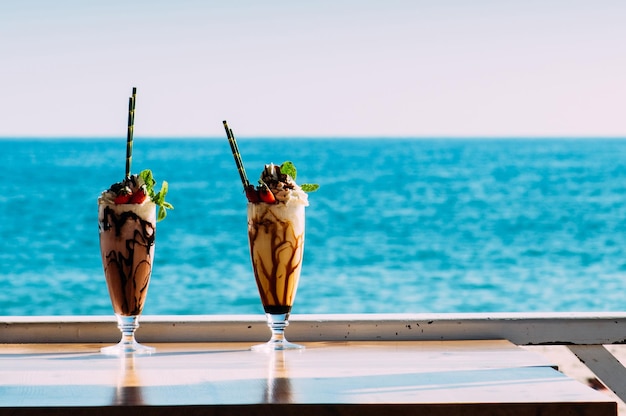 Two delicious sundays on a table overlooking the ocean on a sunny day