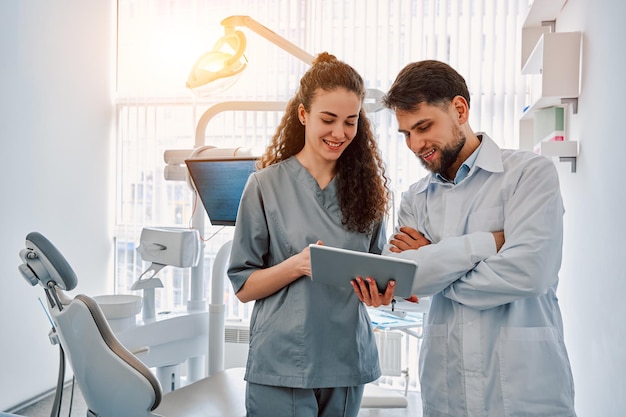 Two dentist doctors are standing in a dental office and looking at a tablet Medicine dentistrySunlight