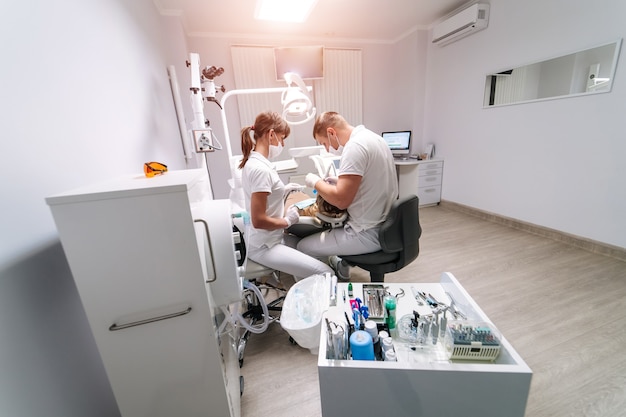 Two dentists examine the patient's teeth for the further treatment