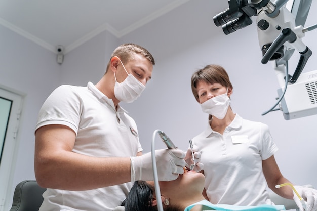 Two dentists examine the patients teeth for the treatment.