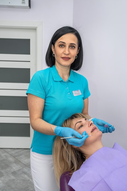 Two dentists women in special clothes look at the teeth of a patient with caries The concept of dental examination before treatment