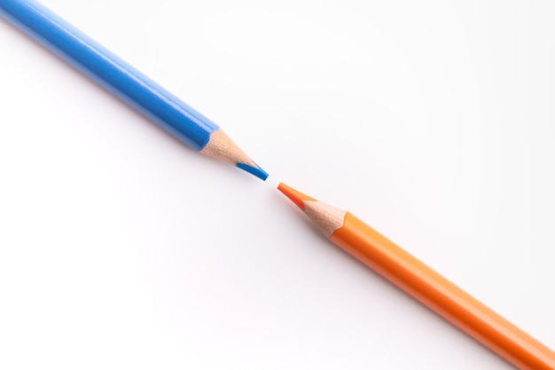 Two diagonal pencils with sharpened tips in complementary colors, blue and orange.